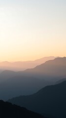 Obraz premium Ultra HD vertical landscape of foggy mountain ridges at sunrise. Pastel sky and warm sunlight create a soft, elegant, and minimal nature scene—ideal for serene visuals.