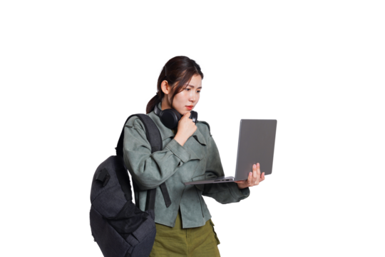 Portrait of Asian female student wearing backpack, headphones, fashionable clothes, holding laptop, posing dynamically on white background