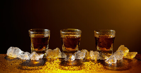 Whiskey and ice on a black table.