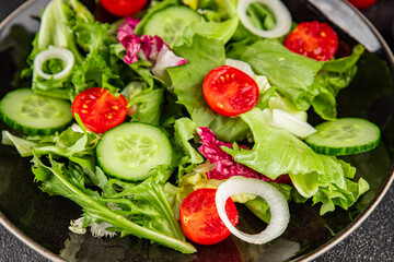 Vegetable salad tomato, cucumber, lettuce, green leaf lettuce, onion appetizer vegetable dish fresh gourmet food background rustic food top view copy space 