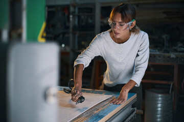 Female worker handling signboard from sawdust in workshop