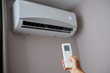 Man sets comfortable temperature for himself in room of 20 degrees Celsius on air conditioner,...