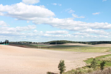 Green Field and Plowed Land Under Blue Sky