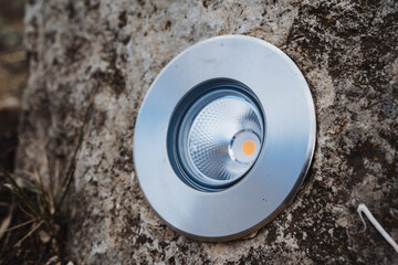 A round light fixture is located atop a large rock, creating a striking visual contrast between the...