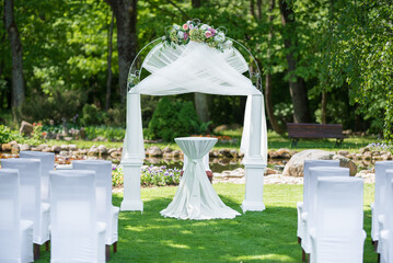 Outdoor Wedding Ceremony Setup in a Green Garden With Chairs and Floral Arch