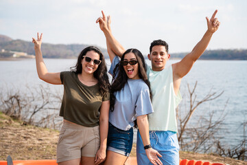 Group of friends thrilled having fun by the lake with an orange kayak, ready for a summer kayaking adventure