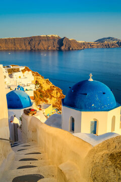 Fototapeta traditional greek village Oia of Santorini, narrow street with blue domes against sea and caldera, Santorini Greece