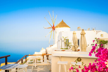 Oia, traditional windmill of white greek village of Santorini against water and sky, Greece