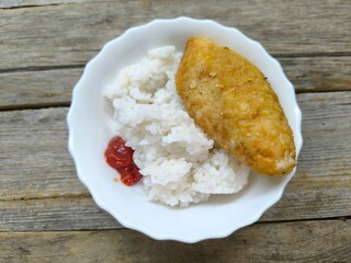 Kyiv cutlet with white rice on a plate on a wooden table