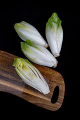 Fresh raw Belgian endives (chicory) on black background