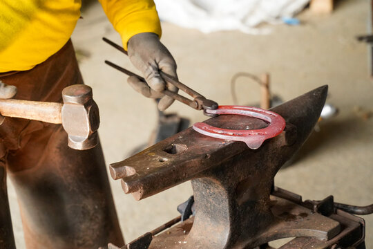 Blacksmith working on a horseshoe on the anvil, and a hammer ready for shaping and repairing