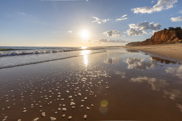 The golden sand beach of Praia da Falésia, crystal-clear sea water at low tide with the reflection...
