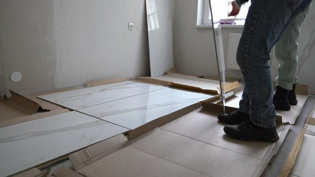The craftsmen lay out the tiles to fit the pattern. Laying large-format porcelain tiles measuring 120 by 60 on the walls. High quality 4k footage