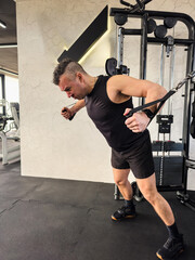 Man performing cable chest fly exercise in modern gym during daytime workout session