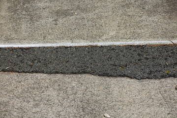 Fototapeta premium Close-up of a concrete sidewalk with a rough asphalt patch repair of uneven pavement