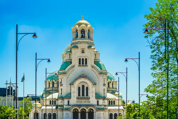 Frontal view of Alexander Nevsky Cathedral in Sofia, Bulgaria, bright sunlight, symmetrical green...