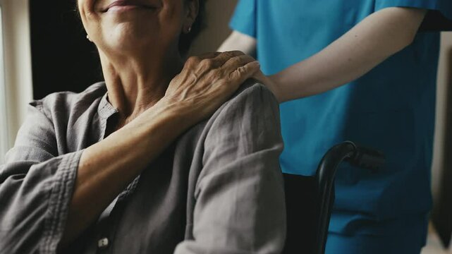 Retirement home nurse placing hand on elderly woman's shoulder, offering support