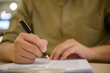 Signature being written on legal form, reflecting business approval, certified paperwork, and...