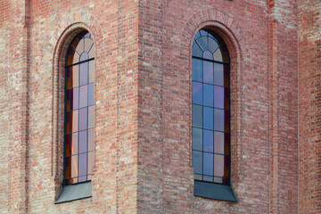 Wall of an old brick building with stained glass windows.