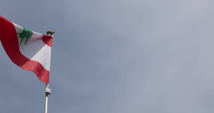 National Flag of Lebanon fluttering in the wind. Great for news. Close-up. Flag of Lebanon against blue sky. 4K video.