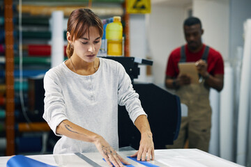 Young woman cutting paper stripes at her workplace in workshop