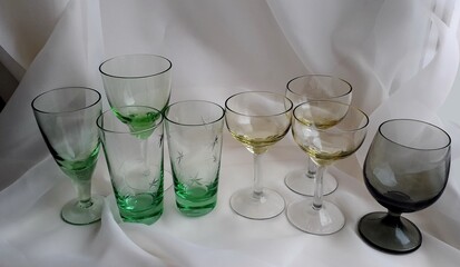 Vintage colored glassware. Colored wine glasses on a light background. Green, burgundy old...