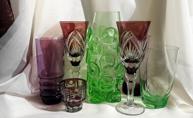 Vintage colored glassware. Colored wine glasses on a light background. Green, burgundy old...