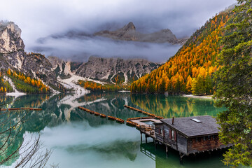 Boating on Lago di Braies in the Italian Dolomites. A calm water surface on which wooden boats are...