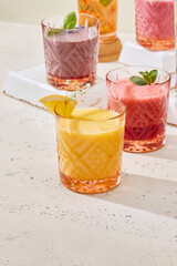 Vibrant Mango Smoothie on Textured White Surface with Colorful Glasses