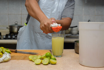 A person squeezes lemons by hand using a manual citrus press by collecting the juice in a glass