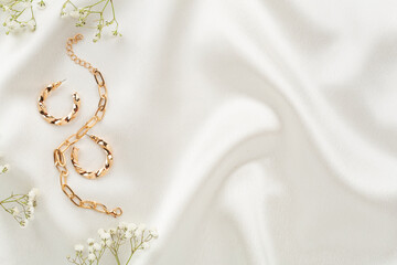 Elegant golden jewelry with decoration on textile background, top view