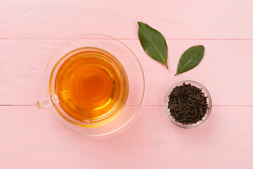 Cup of tea with dry and fresh leaves on wooden background, top view