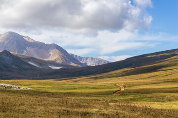 a trail on a mountain plateau located on the path of a tourist route with an overview of the area and the mountain range