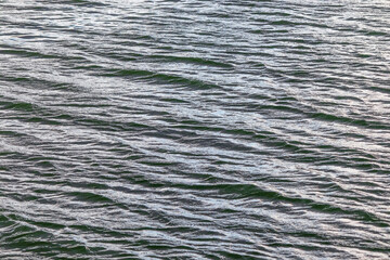 Small wind waves on the water surface. Ripples on the water on a cloudy day - close-up natural background