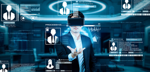 Project manager holding security system hologram and standing at futuristic office with blue glowing color. Business man using augmented reality technology to connect and verify identity. Ingenuity.