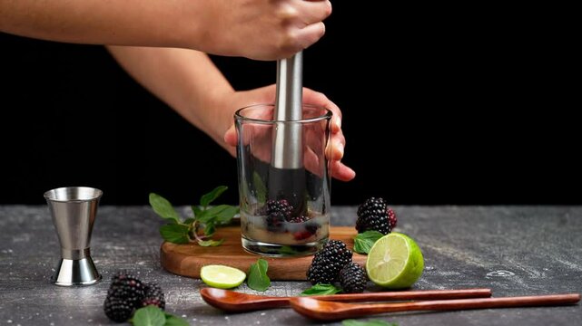 Blackberry mojito, mashing blackberries with a muddler to prepare a mojito