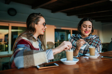 Two women with coffee with milk on the terrace of the bar.