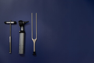 tuning fork C 128 on a blue background with gradation and otorhinoscope and neurological hammer