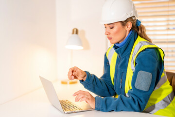 Female construction site manager using laptop in office, focused on project planning and coordination tasks