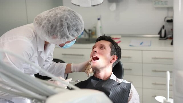 Man is sitting in armchair during dental diagnosis at dentist appointment. Girl doctor conducts examination procedure, identifies problem areas and tests sensitivity of teeth