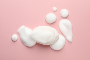 Soap bar with foam on light pink background, top view