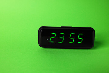 Digital alarm clock showing 23:55 o'clock on green background, space for text