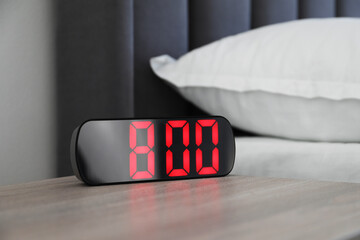 Digital alarm clock showing 8:00 o'clock on bedside table indoors