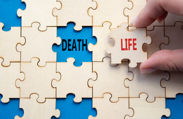 Fototapeta premium Life or Death symbol. Concept word Life or Death on wooden puzzle. Businessman hand. Beautiful blue background. Business and Life or Death concept. Copy space