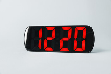 Digital alarm clock showing 12:20 o'clock on grey background