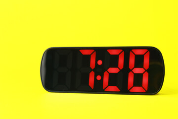 Digital alarm clock showing 7:28 o'clock on yellow background