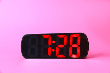 Digital alarm clock showing 7:28 o'clock on pink background