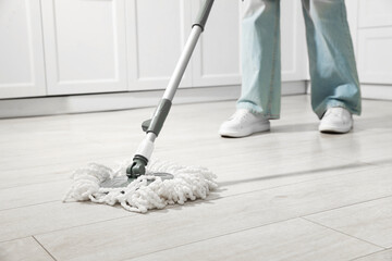Woman cleaning floor with mop at home, closeup
