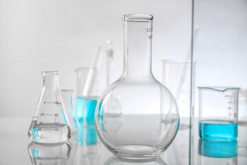Laboratory glassware on mirror surface against light background