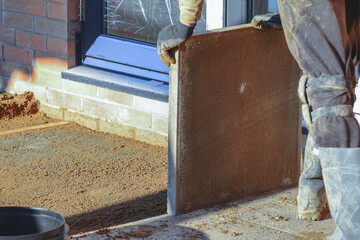 Worker laying concrete paving slab for new patio construction